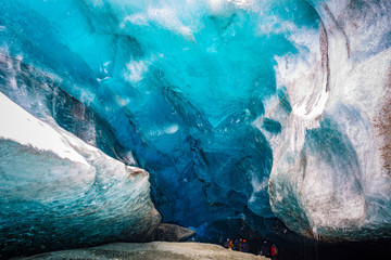 An amazing glacial ice cave entrance with travelers in Iceland