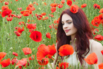 Beautiful redhead woman on a poppy field