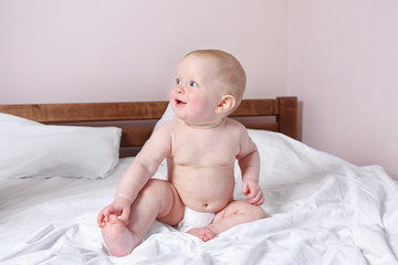 Adorable baby sitting on parents bed, close up