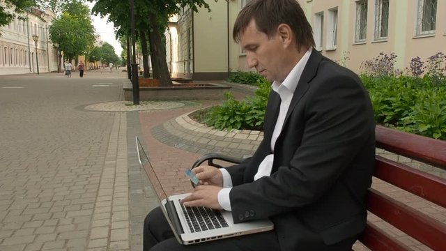 Businessman using his laptop to purchase something online with his credit card