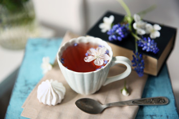 Cup of tea with flowers on wooden stool