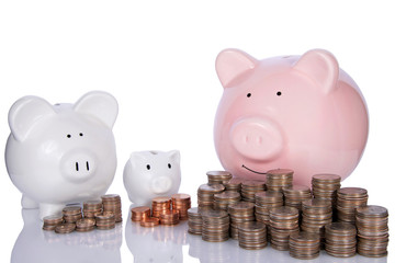 Tiny piggy bank saving pennies, small saving dimes large saving quarters. Small investment building up to larger. Teach children save by example. Younger generation looking up to older wiser parents