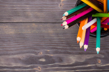 Color pencils in black office bin on dark wooden background