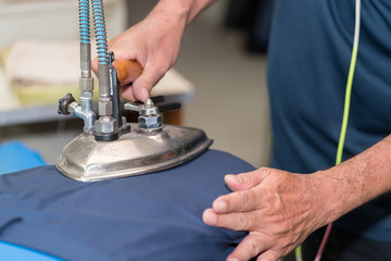 Close-up Of Maid Ironing Clothes On Ironing Board