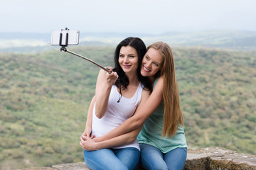 Zwei junge hübsche Frauen machen ein Selfie mit einem Selfie Stick während der Ferien und hab Spaß dabei