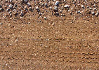 Gravel road surface with trail of wheel.