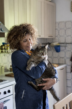 Woman cuddling with cat in kitchen