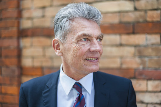 Senior businessman at brick wall looking sideways