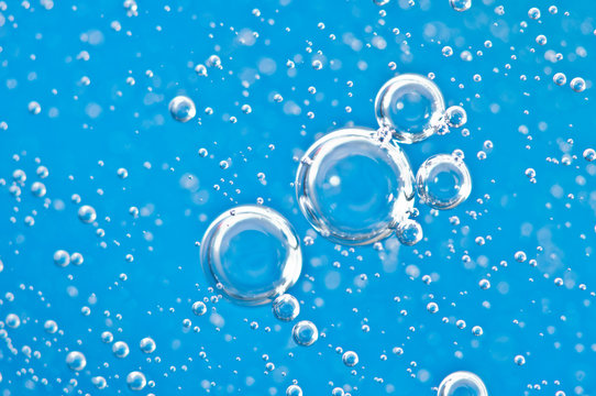 Bright bubbles under water on blue background. Macro.