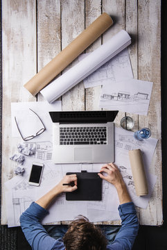Architect working at desk with laptop, making sketches