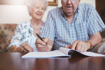 Senior couple signing their will documents - obrazy, fototapety, plakaty