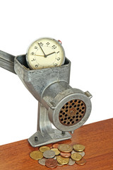 Alarm clock in manual meat grinder and coins on table.