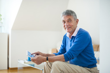 Smiling senior man using digital tablet at home