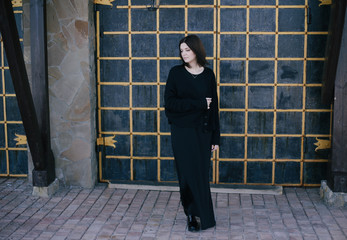 Young woman wearing black clothes posing near gates