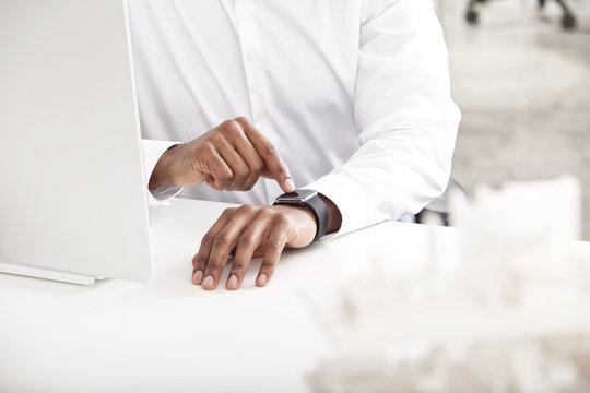 Man's hand adjusting smartwatch at desk