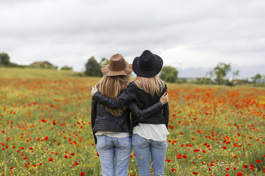 Two woman standing on a poppy field, embracing