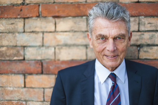 Portrait of confident senior businessman at brick wall