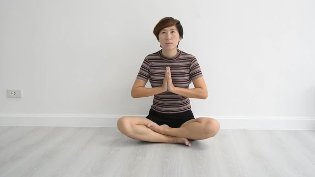 Smart Asian woman meditating in living room