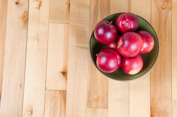red apples in green bowl on wood floor