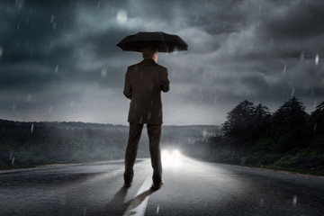 Mann steht im regen auf der Straße.