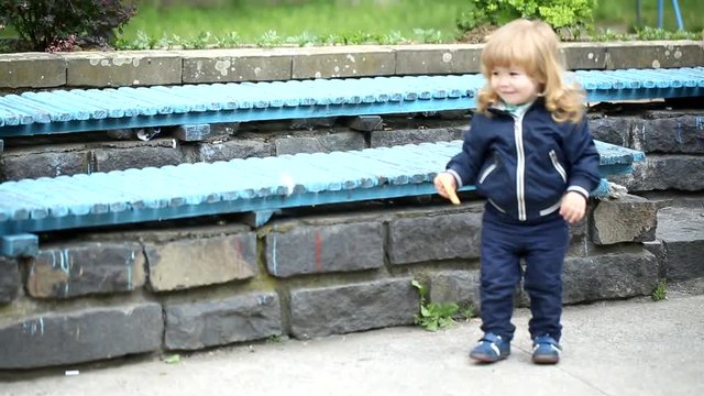 curly-haired boy is jumping with her mother's help from the bench