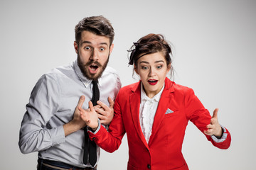 The surprised business man and woman smiling on a gray background