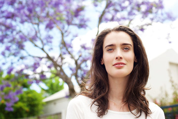 Fototapeta premium Beautiful pensive woman standing in front yard