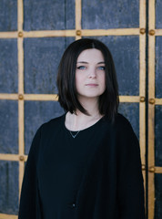 Fototapeta premium Young woman wearing black clothes posing near gates