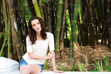 Beautiful young woman sitting by bamboo trees