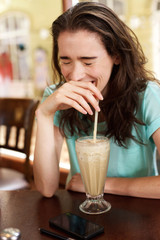 Young woman laughing with milkshake