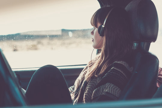 Young woman travelling in car listening music