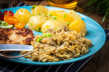 Fried pork chop, baked potatoes and fried young cabbage.