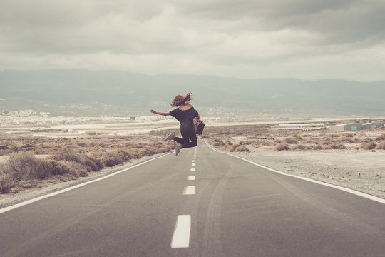 Young woman jumping for joy on a road