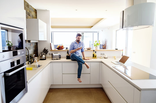 Man sitting in kitchen using smart phone
