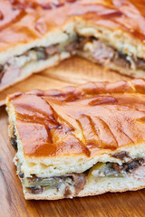 Slice of pie with chicken and mushrooms on a wooden table