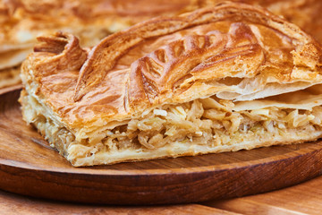 A piece of pie with filling their cabbage on wooden plate
