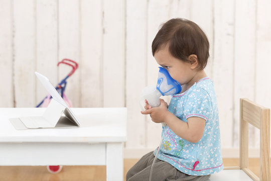 Girl using inhaler looking at digital tablet