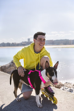 Portrait of smiling inline-skater with his bull terrier