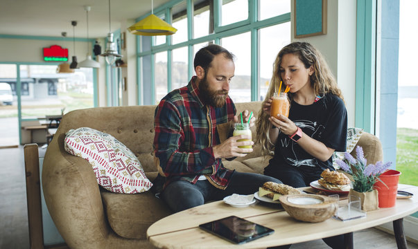 Couple having breakfast in cafe, drinking organic juices