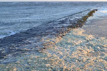 Fototapeten een pier wordt overspoeld door golven en schuim © henkbouwers