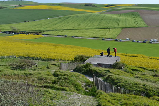 wandelaars op rots kijken naar koolzaadvelden aan de Noordfranse kust