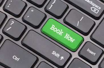 Computer keyboard closeup with "Book Now" text on green enter key