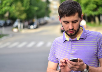 Handsome bearded guy using smartphone outdoors