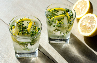 Two glasses of lemonade with thyme, lemon and ice