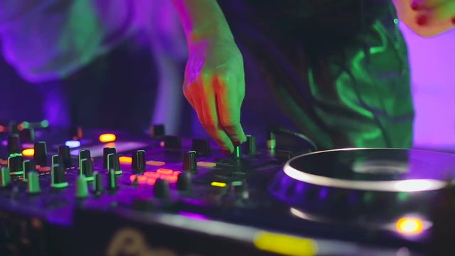 DJ control desk, woman hand mixing, spinning in a Night Club