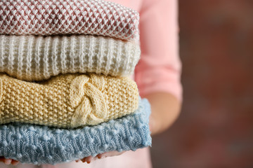 Stack of knitted clothes in female hands closeup