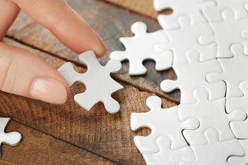 Woman playing with jigsaw puzzle on wooden table