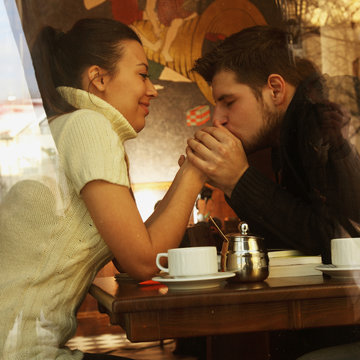 Young happy couple in cafe, view through a window