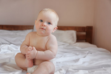 Adorable baby sitting on parents bed, close up