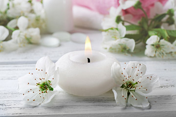 Candle with white flowers on wooden table